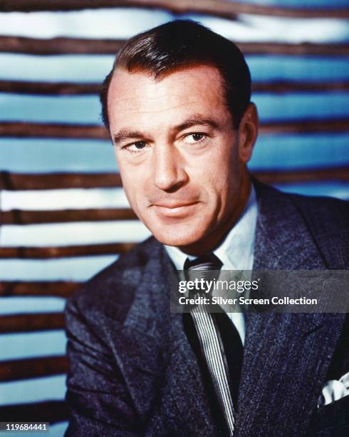 Gary Cooper , US actor, wearing a dark blue jacket, white shirt and black-and-white striped tie, in a studio portrait, circa 1950.