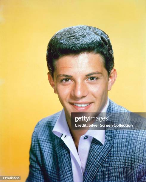 Frankie Avalon, US singer and actor, wearing a blue tweed jacket in a studio portrait, against a yellow background, circa 1960.