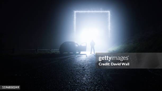 a glowing, portal, gateway on a country road. with a man standing next to a car. on a spooky, foggy, winters night. science fiction concept. - mystery car stock pictures, royalty-free photos & images