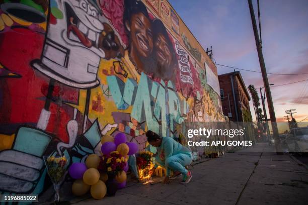 Emily Garbutt lights a candle below a mural by the artists Muck Rock and Mr79lts showing Kobe Bryant and his daughter Gianna Bryant, who were killed...