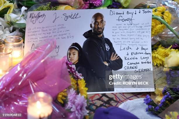 Note is seen among flowers and candles at a makeshift memorial as fans mourn the death of NBA legend Kobe Bryant, who was killed along with his...