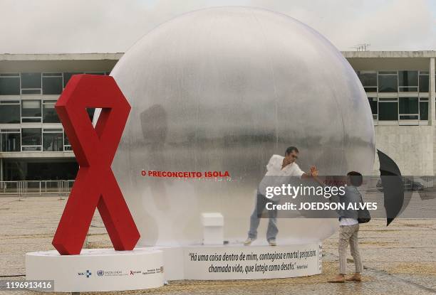 Brazilian actor Romulo Augusto performs inside a plastic bubble to represent AIDS infected people isolated from the society, on December 1 in front...