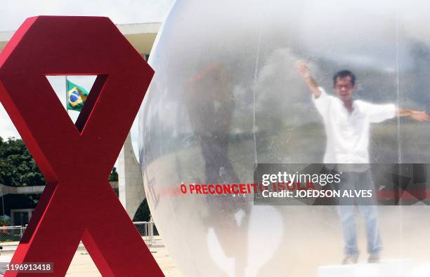 Brazilian actor Romulo Augusto performs inside a plastic bubble to represent AIDS infected people isolated from the society, on December 1 in front...
