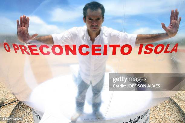 Brazilian actor Romulo Augusto performs inside a plastic bubble to represent AIDS infected people isolated from the society, on December 1 in front...