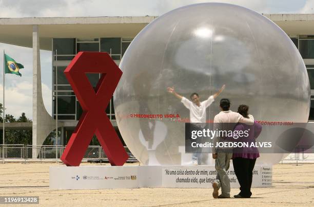 Brazilian actor Romulo Augusto performs inside a plastic bubble to represent AIDS infected people isolated from the society, on December 1 in front...