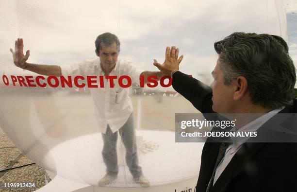 Brazilian actor Romulo Augusto performs inside a plastic bubble to represent AIDS infected people isolated from the society, on December 1 in front...