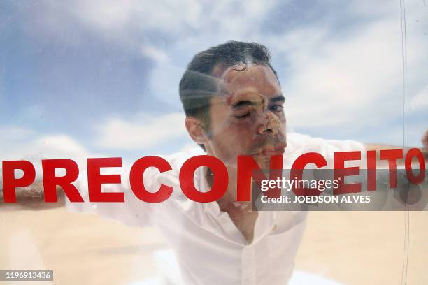 Brazilian actor Romulo Augusto performs inside a plastic bubble to represent AIDS infected people isolated from the society, on December 1 in front...