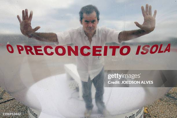 Brazilian actor Romulo Augusto performs inside a plastic bubble to represent AIDS infected people isolated from the society, on December 1 in front...