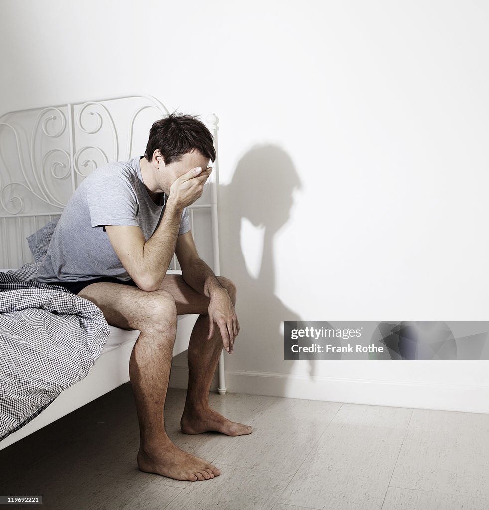 Man waking up in his bedroom while sitting at bed