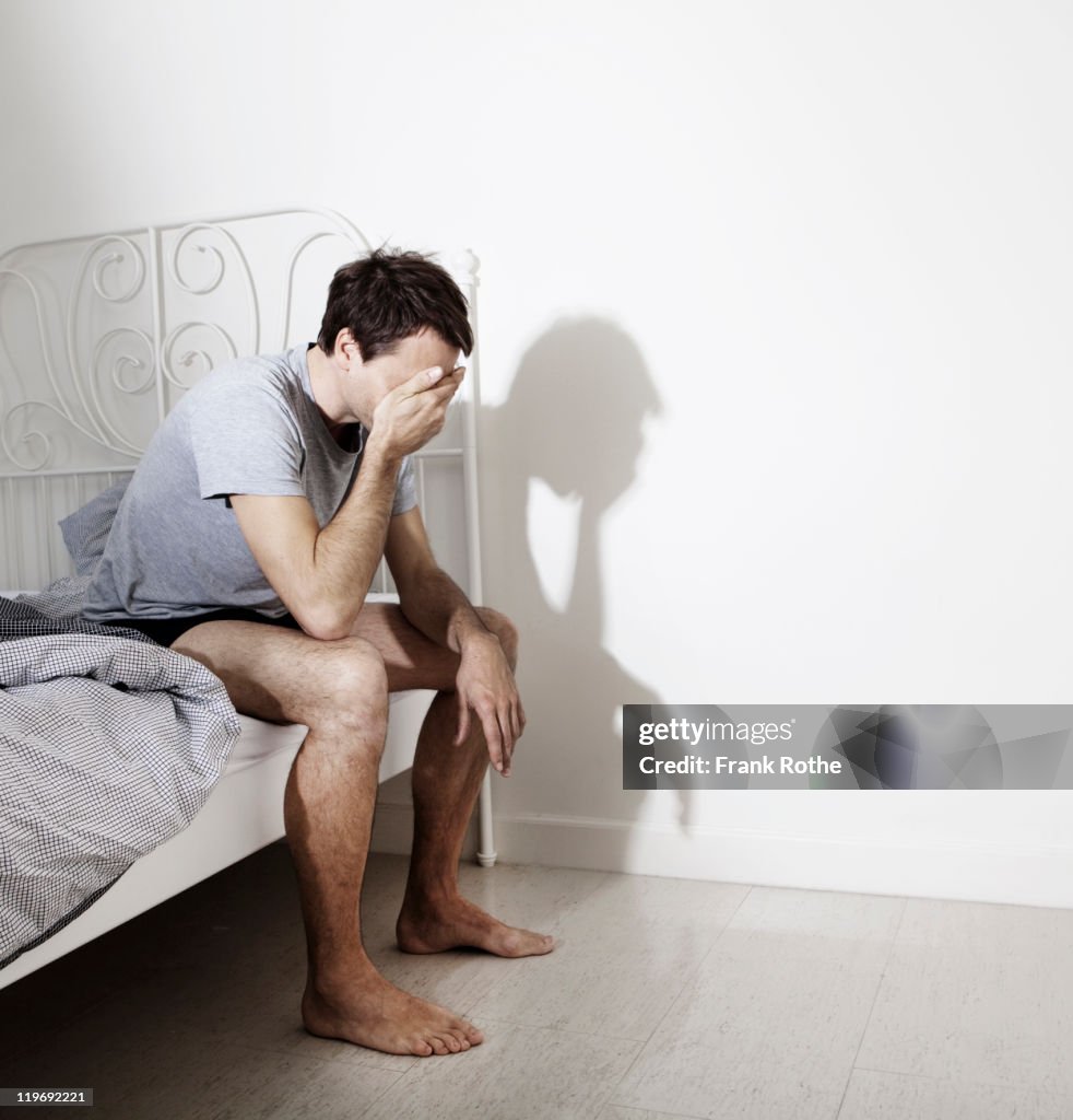 Man waking up in his bedroom while sitting at bed