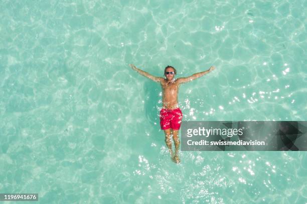 vista de drones del hombre que se relaja en el mar tropical flotando en el agua - floating on water fotografías e imágenes de stock