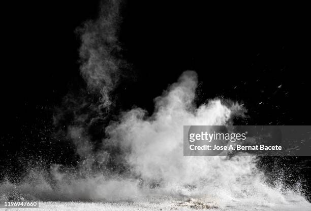 explosion by an impact of a cloud of particles of powder and smoke of white color on a black background. - cloud burst stock pictures, royalty-free photos & images