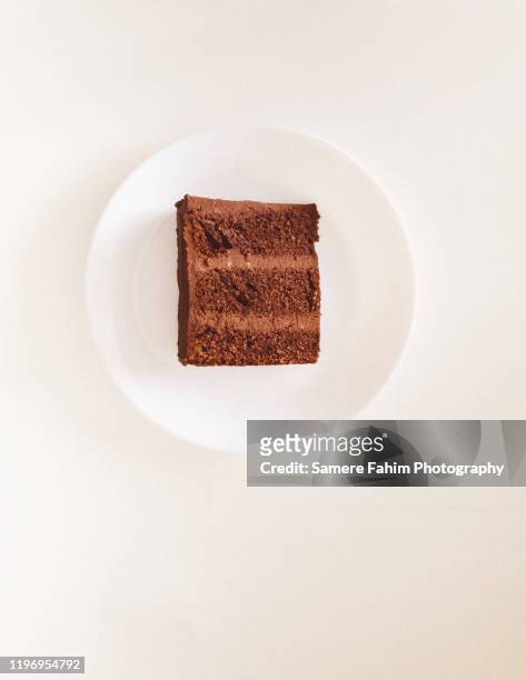 chocolate cake slice with avocado chocolate icing on a plate - slice of cake isolated stock pictures, royalty-free photos & images