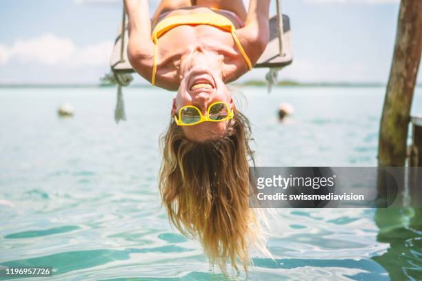 ondersteboven meisje spelen op swing over de zee, mexico - offbeat stockfoto's en -beelden