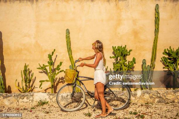 woman with bicycle against cactus wall in mexico - tulum stock pictures, royalty-free photos & images