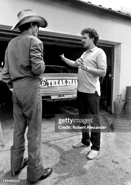 Richard Petty , driver of the STP Pontiac, talks with his son, Kyle Petty, in the garage at the Daytona International Speedway prior to the start of...