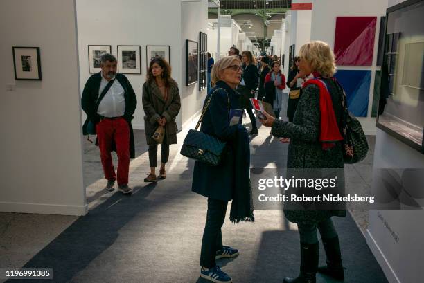 People attending the annual Paris Photo photography art fair meet in a hallway of photographs at the Grand Palais in Paris, France on November 6,...