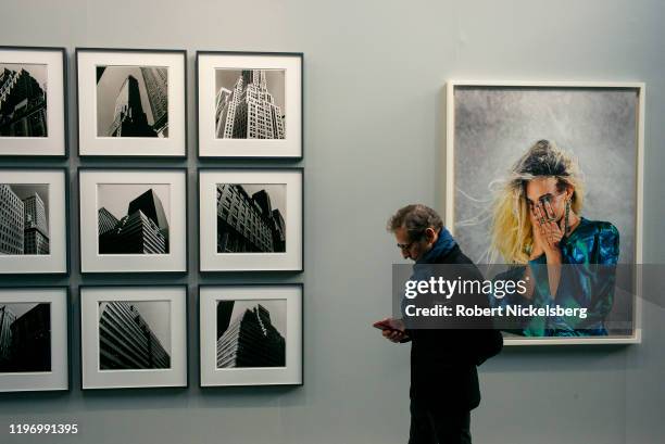 Man attending the annual Paris Photo photography art fair walks down a hallway of photographs at the Grand Palais in Paris, France on November 6,...