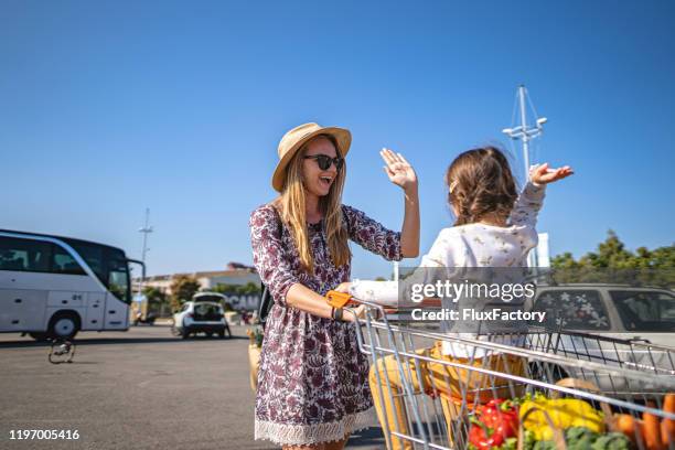 mother and daughter high fiving at the parking lot - man pushing cart fun play stock pictures, royalty-free photos & images