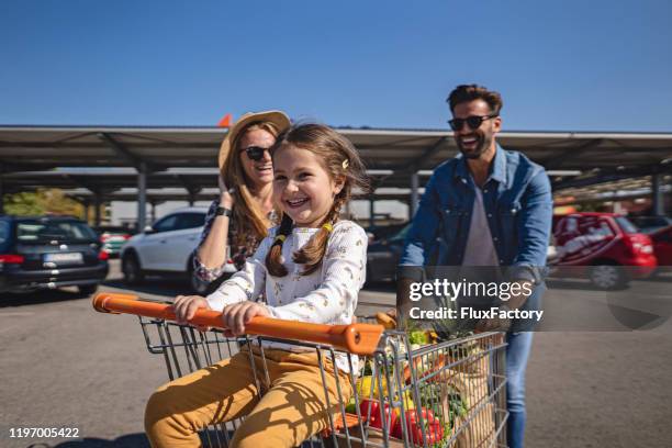 little girl being pushed by dad and mom - man pushing cart fun play stock pictures, royalty-free photos & images