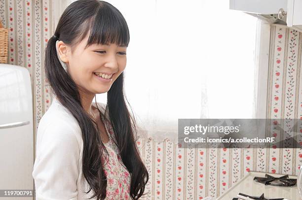 young woman in kitchen - 二つに結んだ髪 ストックフォトと画像