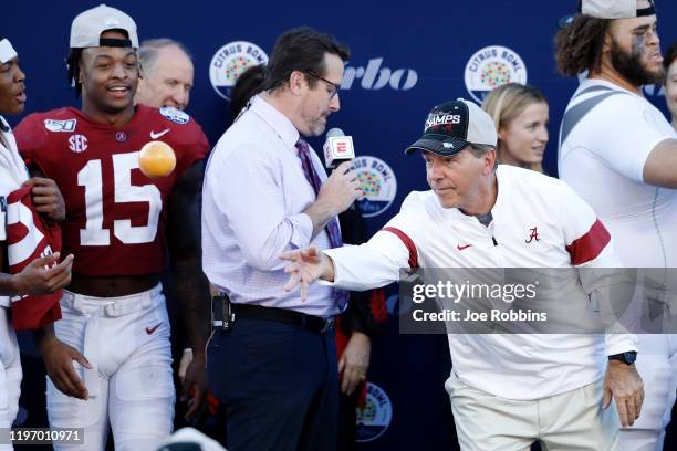 Head coach Nick Saban of the Alabama Crimson Tide tosses oranges to his players following a win against the Michigan Wolverines in the Vrbo Citrus...