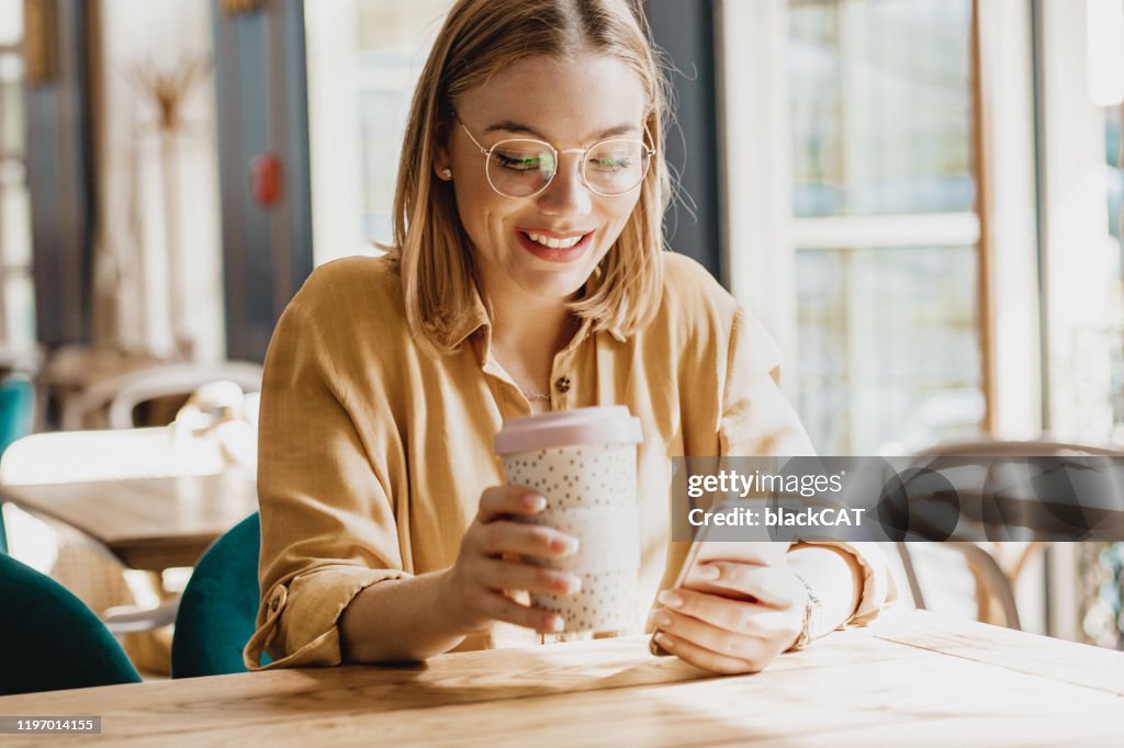 Young woman in cafeteria using phone