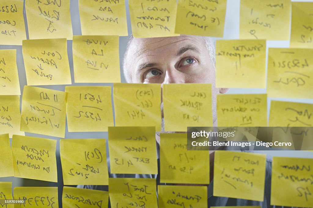 Caucasian businessman looking at adhesive notes on wall