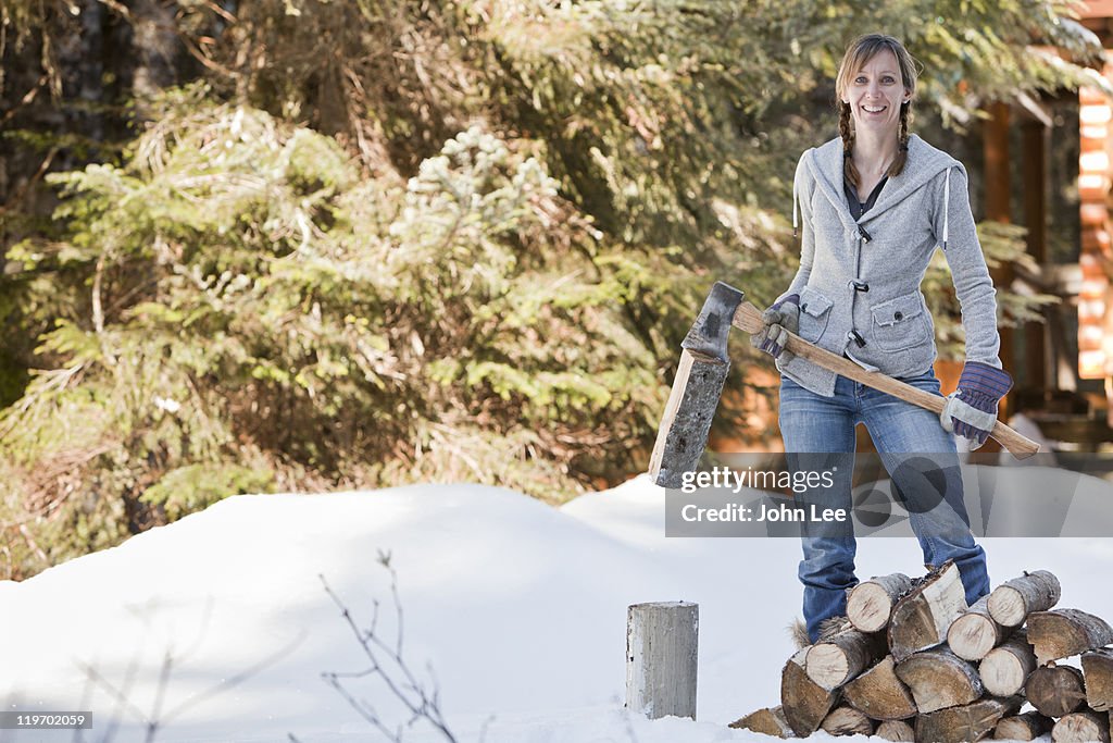 Caucasian woman chopping firewood in snow