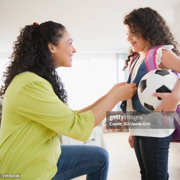 mother dressing daughter holding soccer ball - soccer mom stock pictures, royalty-free photos & images