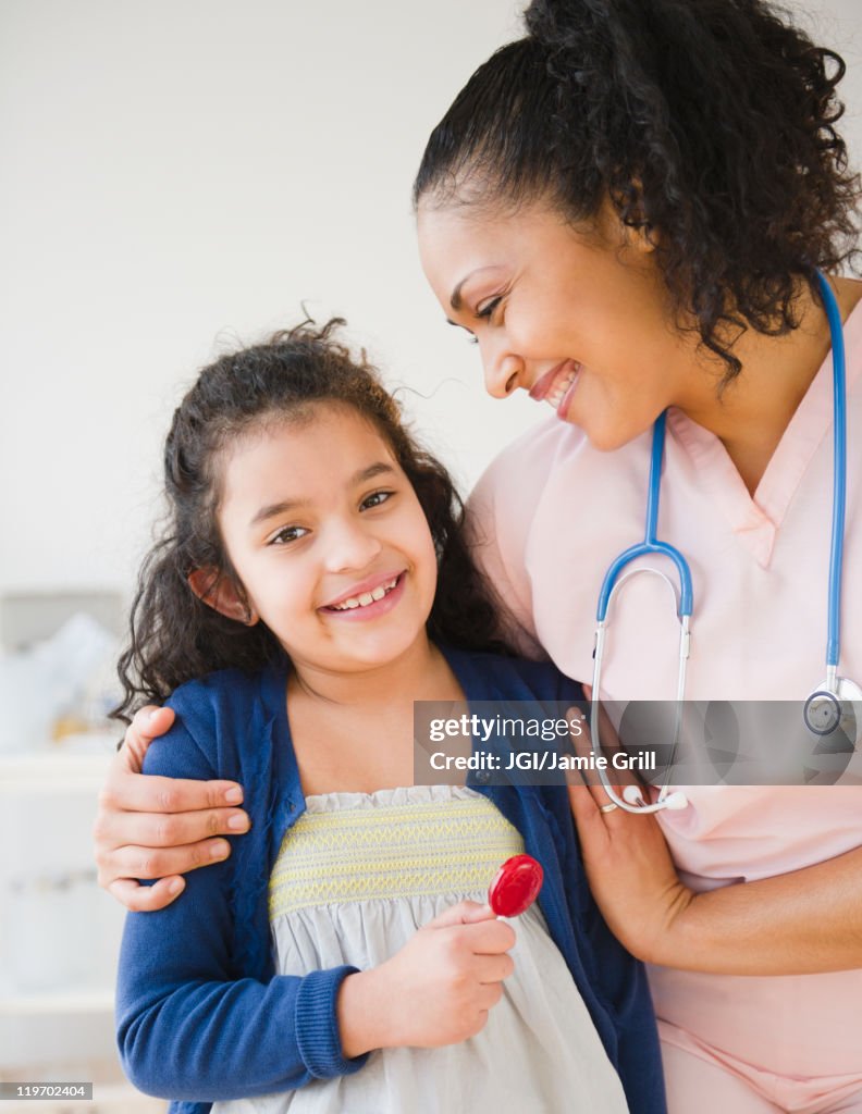 Smiling nurse giving girl lollipop