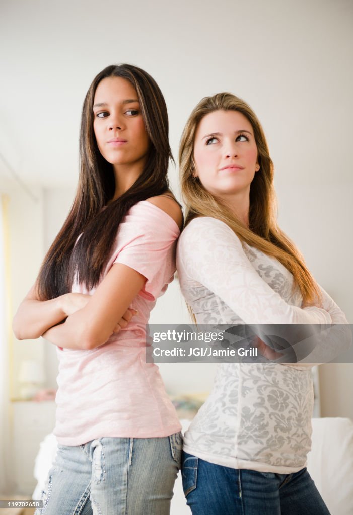Teenage girls standing back to back
