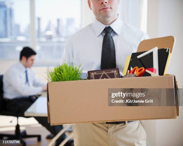 fired caucasian businessman carrying personal belongings - despedida fotografías e imágenes de stock