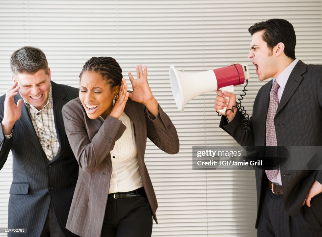 Businessman shouting through bullhorn at co-workers