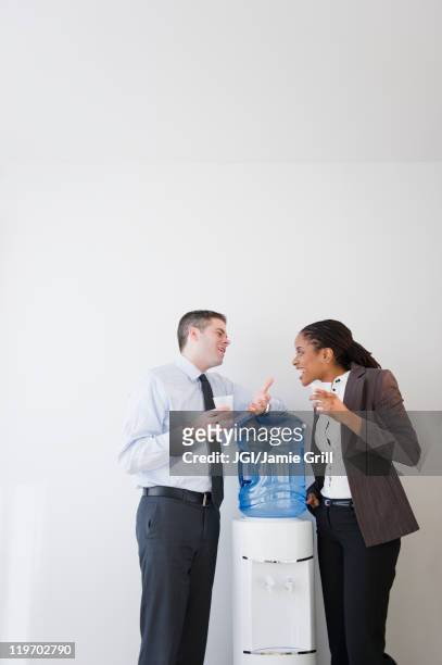 business people talking together at water cooler - trinkwasserbehälter stock-fotos und bilder