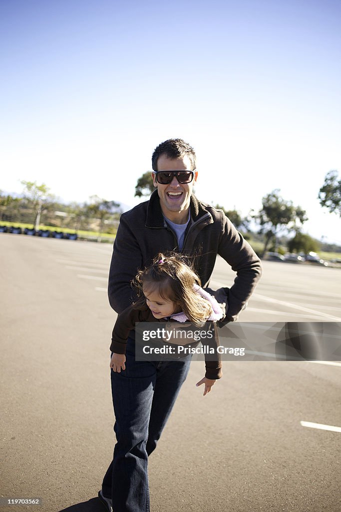 Father carrying daughter in parking lot