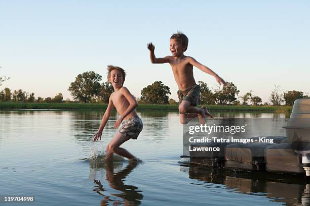 usa, texas, texarkana, two boys (8-9) jumping into lake - texas family stock pictures, royalty-free photos & images