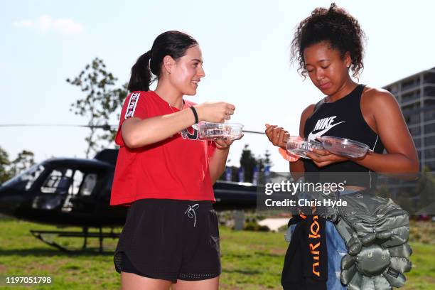 Kim Birrell of Australia and Naomi Osaka of Japan eat lamington after a helicopter tour of Brisbane ahead of the 2020 Brisbane International at Pat...