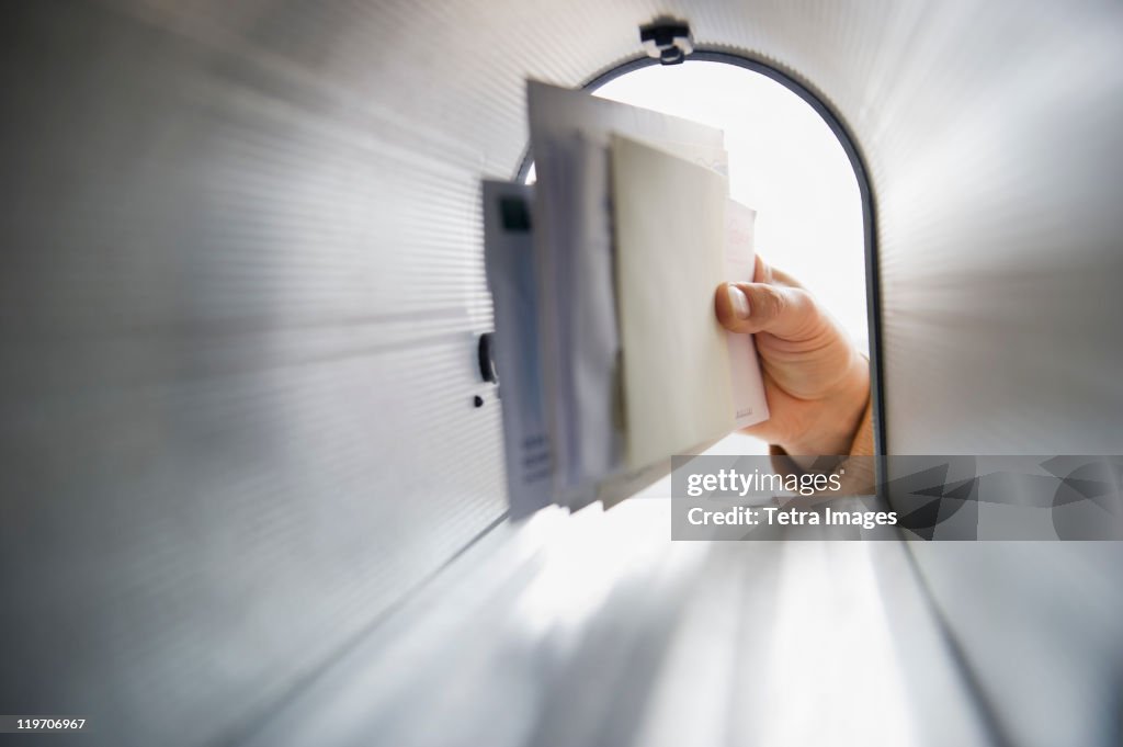 Close-up of man's hand removing letters from letter box