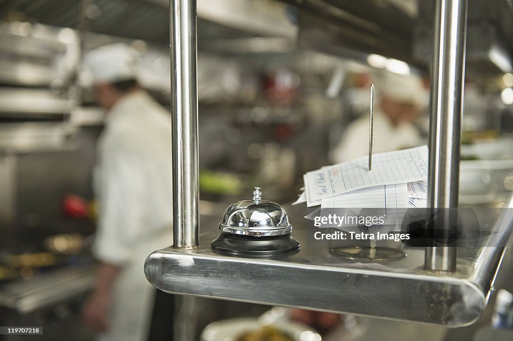 USA, New York State, New York City, Chefs preparing food in kitchen, focus on service bell on foreground