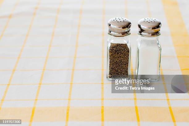 salt and pepper shakers on checked tablecloth - 胡椒入れ ストックフォトと画像