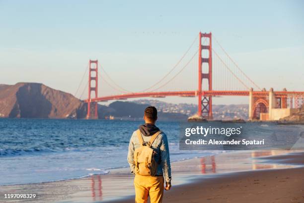 tourist with backpack looking at golden gate bridge, san francisco, california, usa - tour of california stock-fotos und bilder