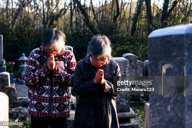 二人の先輩日本人女性が墓地で手を合わせた - cemetery ストックフォトと画像