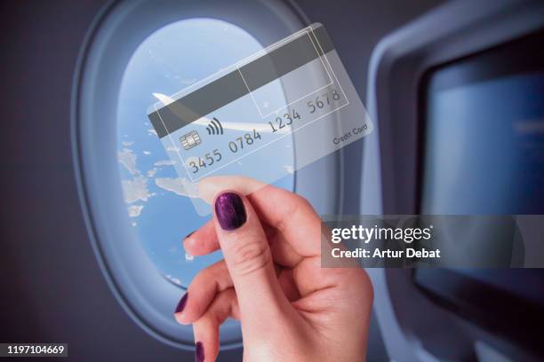 holding transparent credit card traveling with airplane with window view. - travel credit card stock pictures, royalty-free photos & images