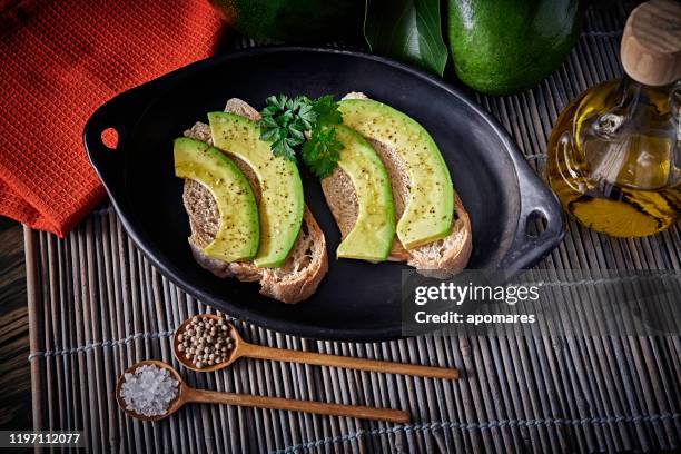 low-key-bild von tapas, snack oder vorspeise von avocado-scheiben bruschetta mit olivenöl, pfefferminze und salz - aguacates stock-fotos und bilder