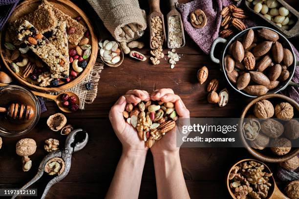 vrouw handen houden een verscheidenheid van gedroogde vruchten en noten op een tafel in een ouderwetse rustieke keuken - gedroogd fruit stockfoto's en -beelden
