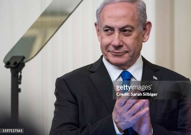 Israeli Prime Minister Benjamin Netanyahu listens as U.S. President Donald Trump speaks during a joint statement in the East Room of the White House...