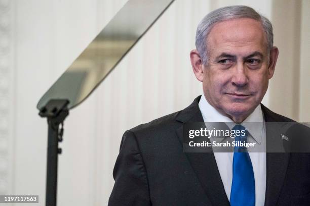 Israeli Prime Minister Benjamin Netanyahu listens as U.S. President Donald Trump speaks during a joint statement in the East Room of the White House...