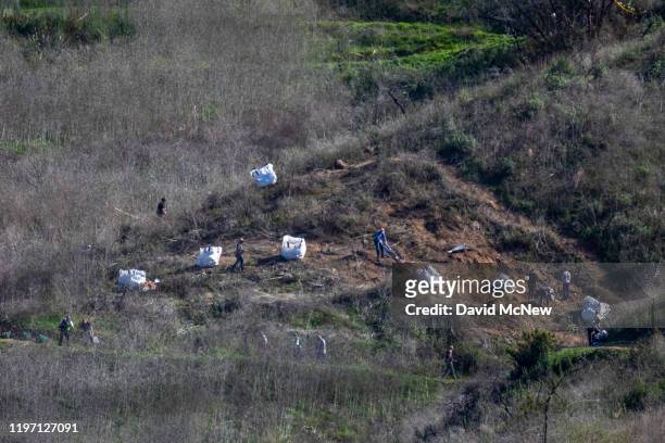 Investigators work at the scene of the helicopter crash, where former NBA star Kobe Bryant and his 13-year-old daughter Gianna died, on January 28,...