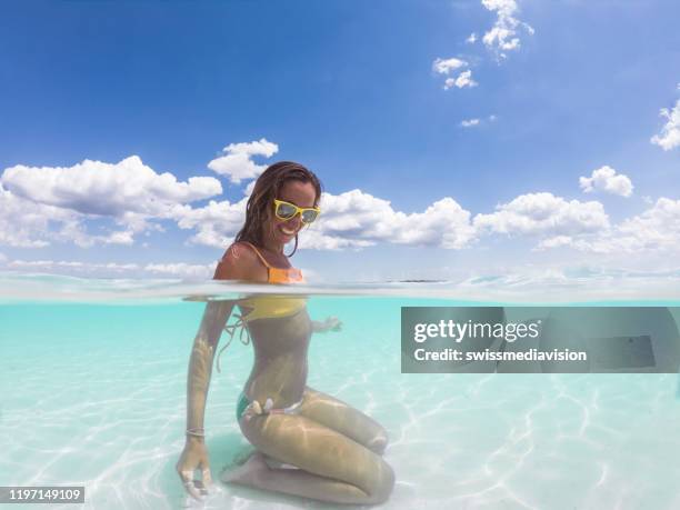 underwater shot of woman relaxing on idyllic beach - half stock pictures, royalty-free photos & images